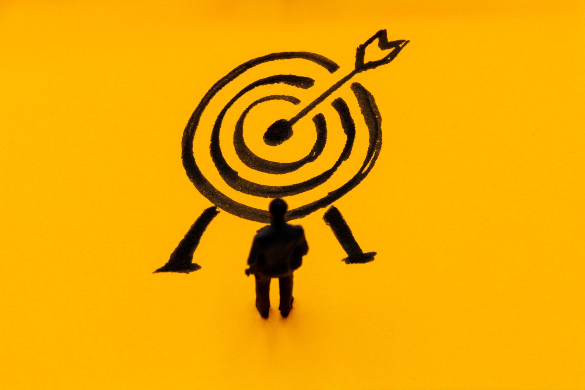 Miniature figurine posed as businessman in front of target, performance concept image